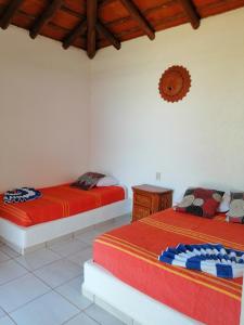 Casa La Quinta Ola في ترونكونيس: سريرين في غرفة بجدران بيضاء