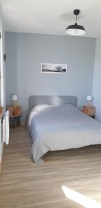 a white bedroom with a bed and two night stands at La petite maison in Saint-Aignan