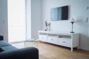 een woonkamer met een witte dressoir en een tv. bij Prime Park Family Apartment Aschaffenburg in Aschaffenburg