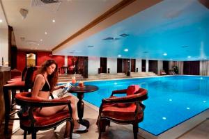 une femme assise à une table devant une piscine dans l'établissement Grand Monastery Private Apartment, à Pamporovo