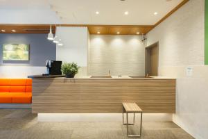 a lobby with an orange couch and a counter at Tokyu Stay Yoga in Tokyo