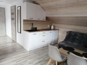 a kitchen with white cabinets and a table and chairs at PAKLADA 3 Pokój typu studio in Karsin