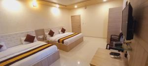 ein Schlafzimmer mit zwei Betten und einem Flachbildfernseher in der Unterkunft Sanjog Resort in Kota