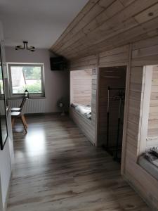 PAKLADA 3 Pokój typu studio في Karsin: غرفة ذات أرضيات خشبية وغرفة بها سريرين