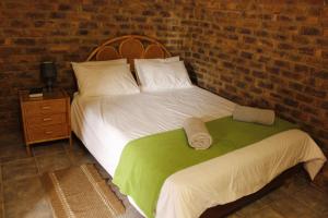 a bedroom with a bed and a brick wall at El Rancho Grande in Warmbaths