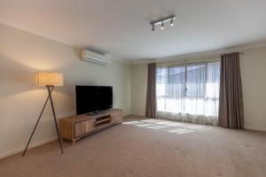 a living room with a flat screen tv and a lamp at Immaculate House, Indulgent Living! in Brisbane