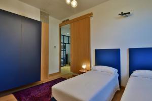 sypialnia z 2 łóżkami i niebieską ścianą w obiekcie Casa Rebecca w mieście Riposto