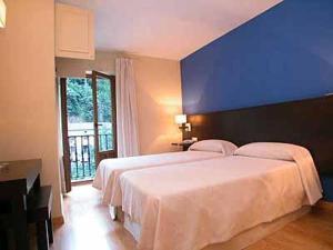 um quarto com uma grande cama branca e uma parede azul em Hotel Cosgaya em Cosgaya