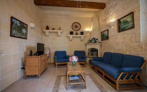 ein Wohnzimmer mit blauen Sofas und einem Kamin in der Unterkunft Lighthouse Accommodations - Ta’ Mikiel u ta’Marija in Qala