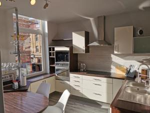 a kitchen with white cabinets and a wooden table at Vakantiehuis H&A 4 sterren in Ieper
