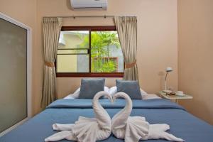 two swans making a heart shape on a bed at Maikhao Home Garden Bungalow in Mai Khao Beach +86 photos