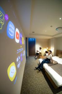 two people sitting on a bed in a hotel room at Hotel S-Presso South in Osaka