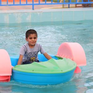 een jonge jongen op een vlot in een zwembad bij بيرحاء إبراء للسياحة in Ibrā