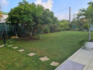 a backyard with a lawn with trees and plants at Villa Lawrencia, meublé de tourisme 4 étoiles in Morne-à-lʼEau