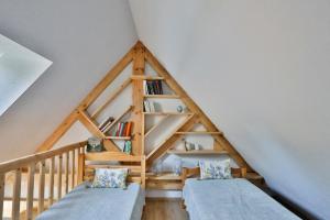 Habitación en el ático con 2 camas y estante de libros en Des Feuilles et Des Hiboux, en Plescop