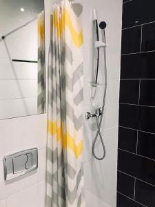 una ducha con cortina de ducha amarilla y blanca en Apartamenty Wojewódzka en Katowice