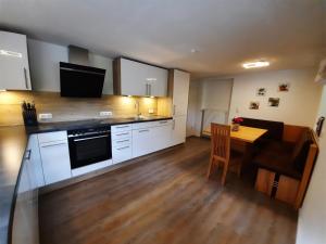 a kitchen with white cabinets and a table and a dining room at Ferienwohnung Kiliansblick in der Kilianmühle in Berchtesgaden