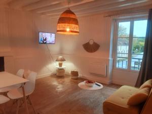 a living room with a couch and a table at Maison avec jardin dans petit bourg typiquement Percheron - Le Colombier in Boissy-Maugis