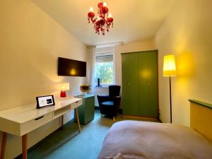 a bedroom with a bed and a desk and a chair at Hotel Ambiente et Art in Düsseldorf