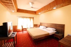 a hotel room with a bed and a television at Vardaan Hotels - PatniTop in Patnitop