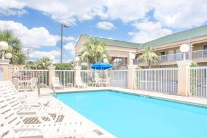 a swimming pool with lounge chairs and a hotel at Baymont by Wyndham Crestview in Crestview