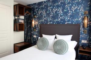 um quarto com uma cama com almofadas brancas e papel de parede azul em Moris Grands Boulevards em Paris