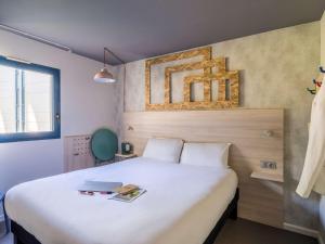 - une chambre avec un grand lit et un ordinateur portable dans l'établissement greet Hotel Bordeaux Aeroport, à Mérignac