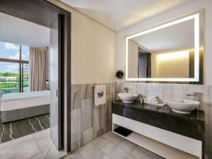 a bathroom with a tub, sink and mirror at Th8 Palm Jumeirah, Accor in Dubai