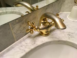 ein Waschbecken mit einem goldenen Wasserhahn auf der Theke in der Unterkunft Hotel Ambiente et Art in Düsseldorf