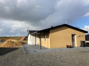 a yellow building with a black roof on a gravel lot at Bakkebo in Hvide Sande