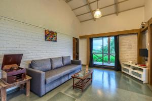 uma sala de estar com um sofá e uma grande janela em SaffronStays Le Soil, Igatpuri - pet-friendly villa with viewing deck for panoramic views em Igatpuri
