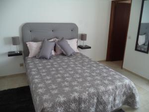 1 dormitorio con cama con edredón y almohadas grises en Quartos Maria Clara, en Sagres