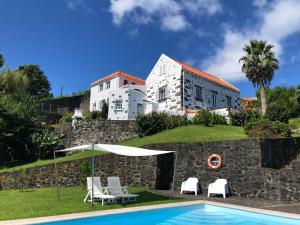 eine Villa mit einem Pool vor einem Gebäude in der Unterkunft Vivenda Flores - Apartment Hibisco in Lomba