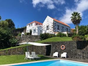 a villa with a swimming pool in front of a building at Vivenda Flores - Apartment Hibisco in Lomba