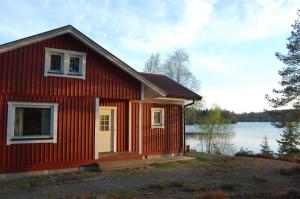a red house on the shore of a lake at Holiday house in Gnosjo with amazing lake view in Gnosjö
