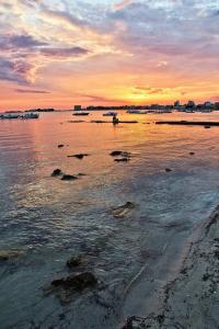 una puesta de sol sobre un cuerpo de agua con rocas en Evergreen B&B, en Porto Cesareo