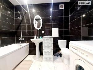 Baño de azulejos negros con lavabo y aseo en Family and friends apartment, en Ternopilʼ