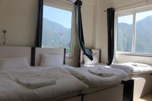 two beds in a room with two large windows at Back Stayz Hostel in Rishīkesh