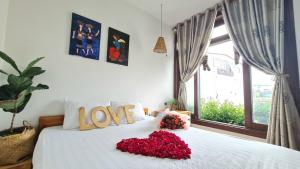 ein Schlafzimmer mit einem weißen Bett mit einem Liebesschild darauf in der Unterkunft Hotel Làng Kò Hơ in Da Lat