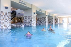 a man and two children swimming in a swimming pool at RCN Vakantiepark de Schotsman appartement De Caisson in Kamperland