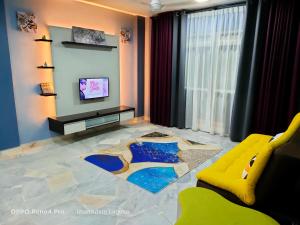 a living room with a yellow couch and a tv at imanAdam Laguna Apartment in Port Dickson
