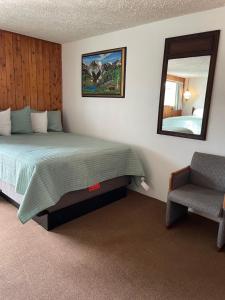 a bedroom with a bed and a mirror and a chair at adoba® Dreamland in Gulliver