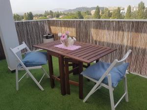 un tavolo in legno e 2 sedie su un patio di The Roses - Delizioso attico su 2 livelli zona Palacongressi a Rimini