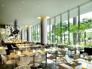 PARKROYAL COLLECTION Pickering, Singapore في سنغافورة: مطعم بطاولات وكراسي ونوافذ كبيرة