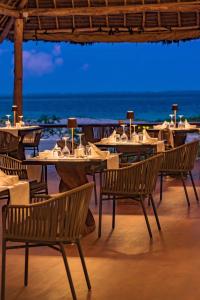 un restaurante con mesas y sillas en la playa en Amani Boutique Hotel - Small Luxury Hotels of the World en Paje
