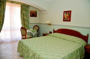 Schlafzimmer mit einem Bett mit grüner Tagesdecke in der Unterkunft Afrodite Boutique Hotel in Bovalino Marina