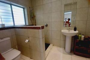 een badkamer met een wastafel, een toilet en een spiegel bij Glencairn Vista in Kaapstad