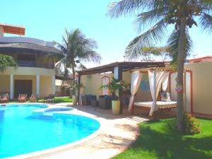 a swimming pool next to a house with palm trees at Villa Serena in Canoa Quebrada