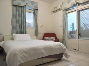 una camera da letto con un letto, una sedia e una finestra di 豪鵬遊民宿2館 a Jincheng