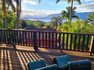 a deck with a view of the ocean and palm trees at Pousada Por do Sol in Ilhabela